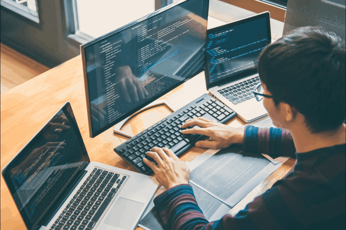 person working on laptops with multiple screens