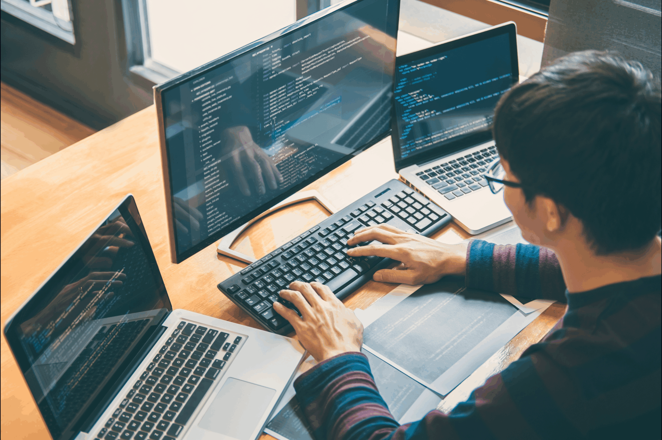 person working on laptops with multiple screens